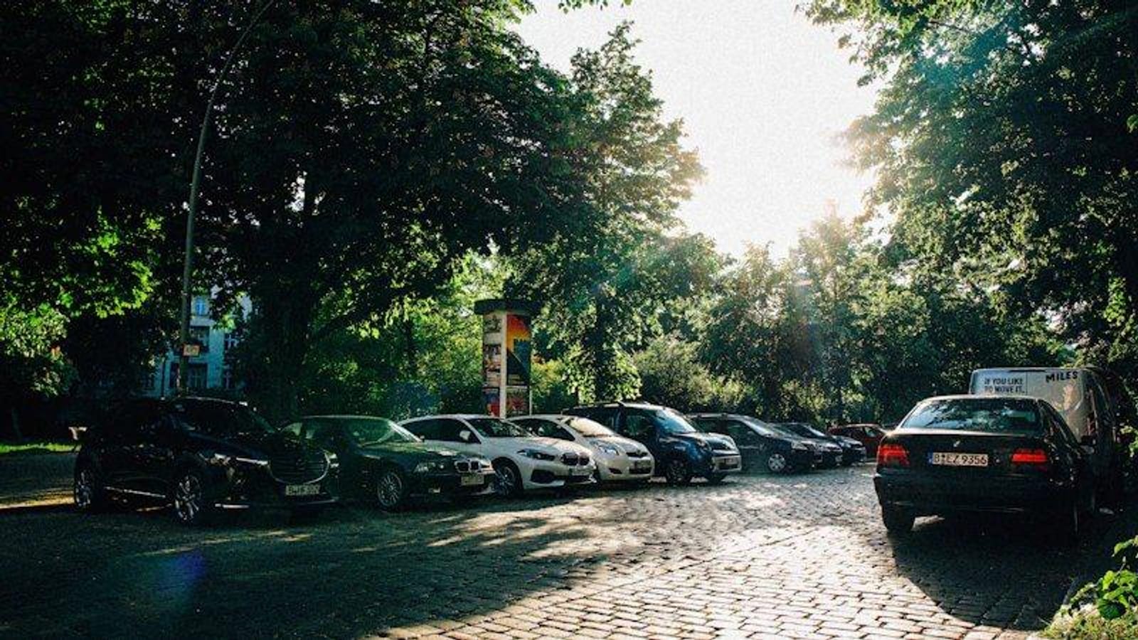 Parkende Fahrzeuge an einer von Bäumen gesäumten Wohnstraße